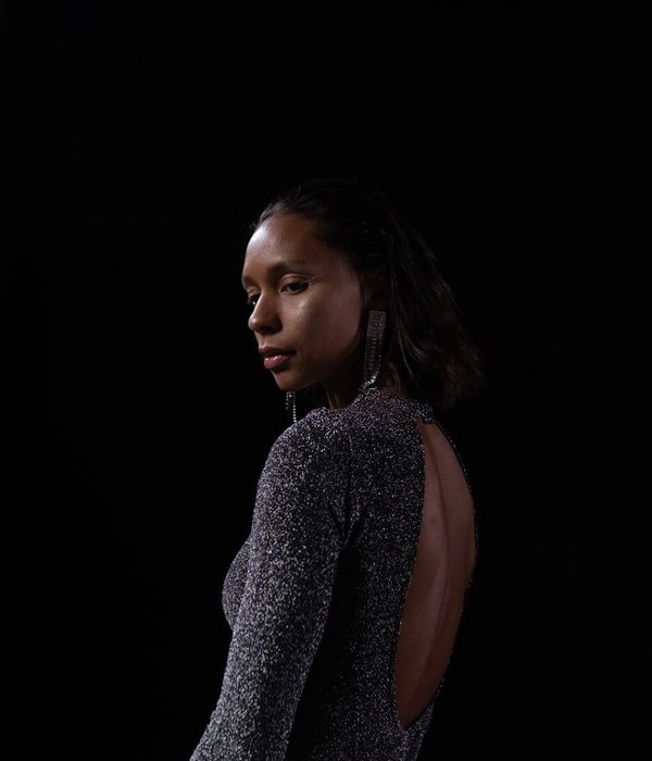 Woman in a calm balancing yoga pose in a dark studio.